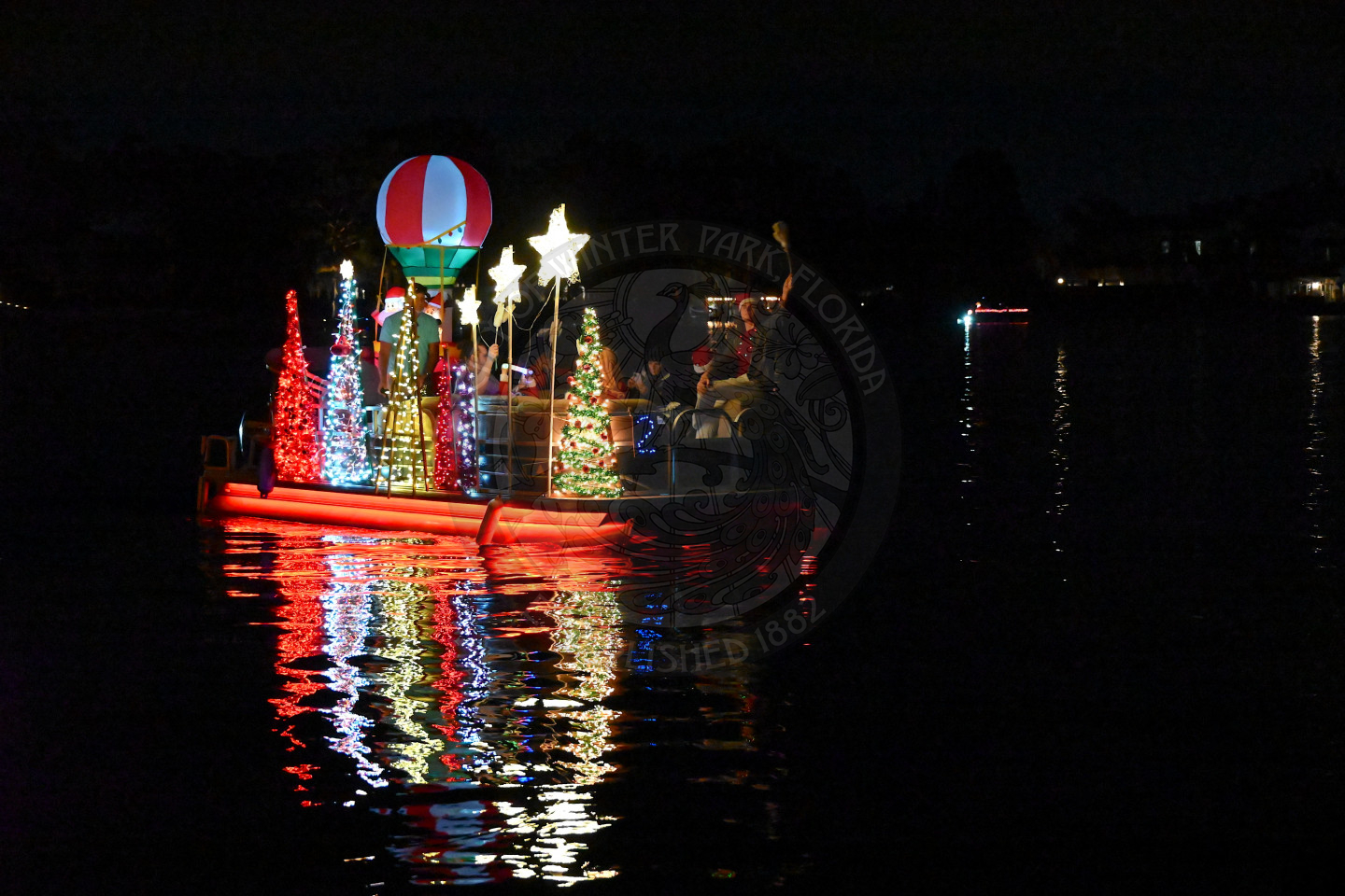 A boat cruising at night, brightly decorated with colorful holiday lights.