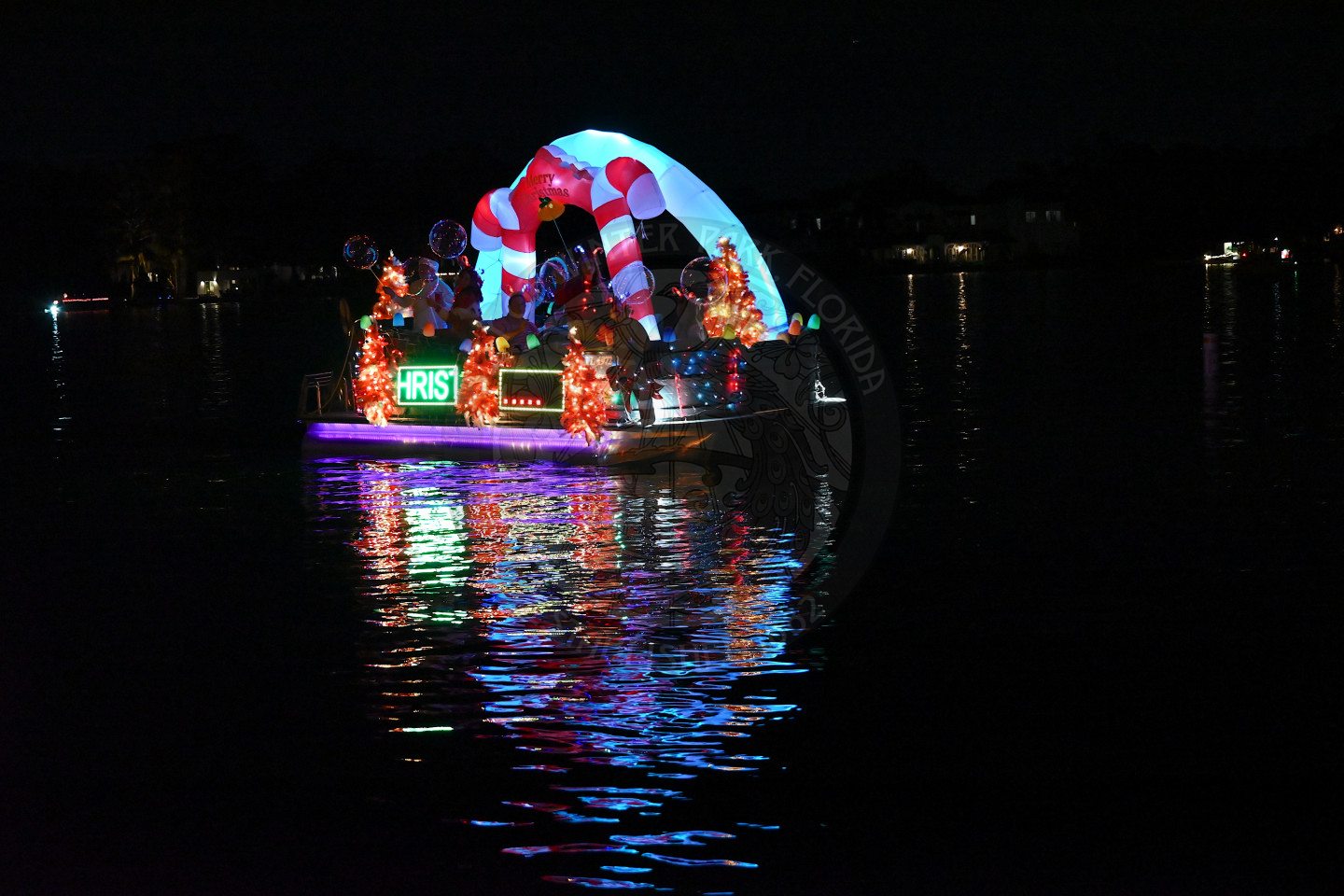 A boat cruising at night, brightly decorated with colorful holiday lights.
