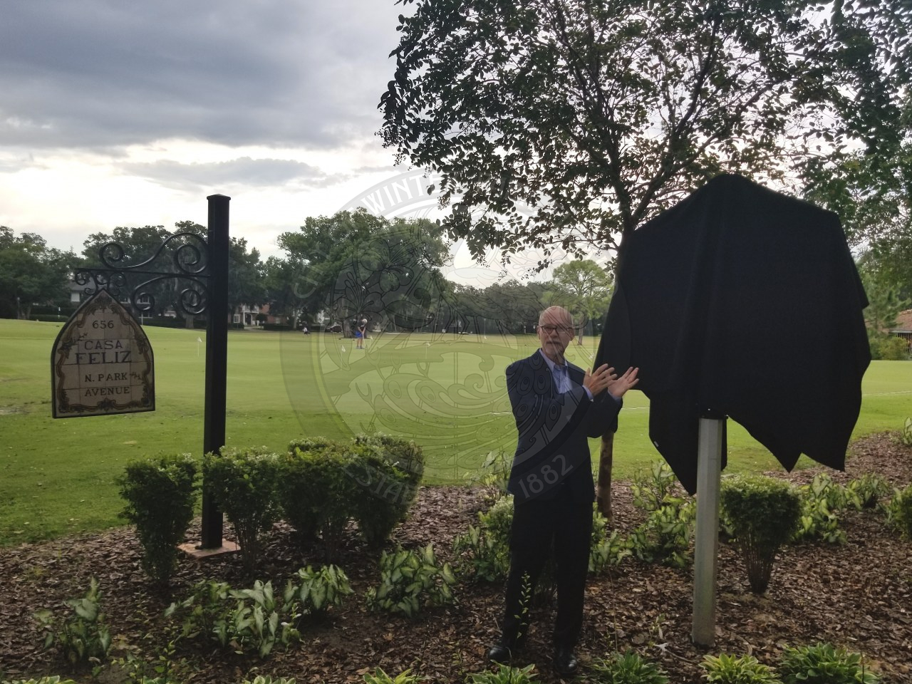 male pointing to an the historic marker that is covered with a sheet