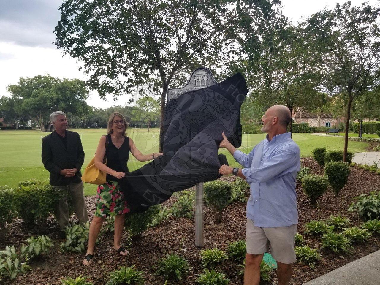male and female pulling a sheet off the covered historic marker