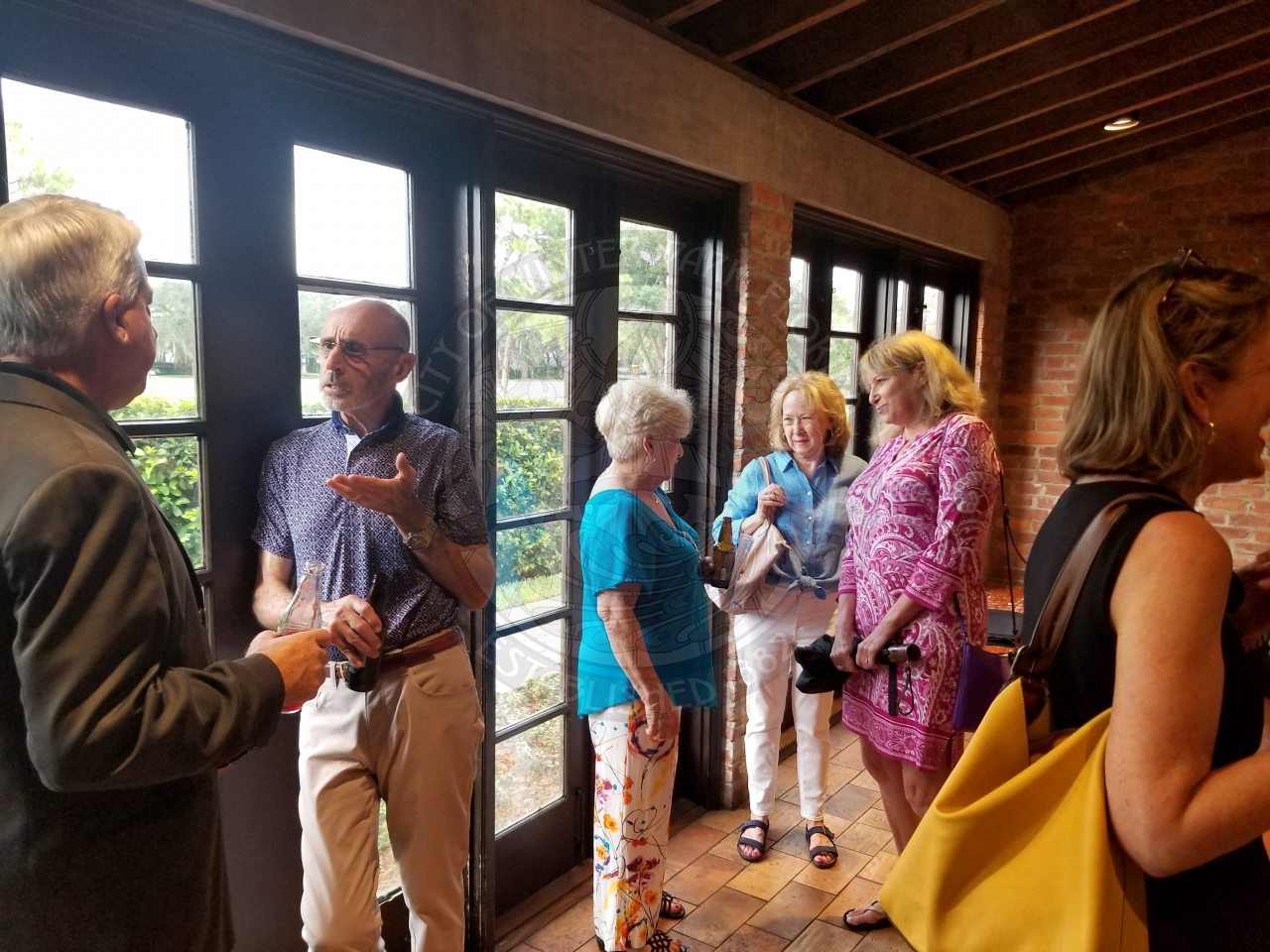 group of people gathered around a room talking to one another
