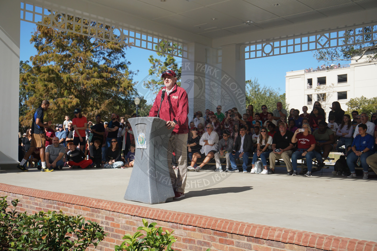 FSU representative standin on stage behind podium introducing the band and song they are going to be playing