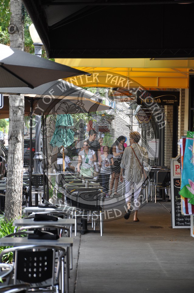 View of Park Avenue under the canopies of the stores with shoppers and outdoor cafes lining the sidewalk