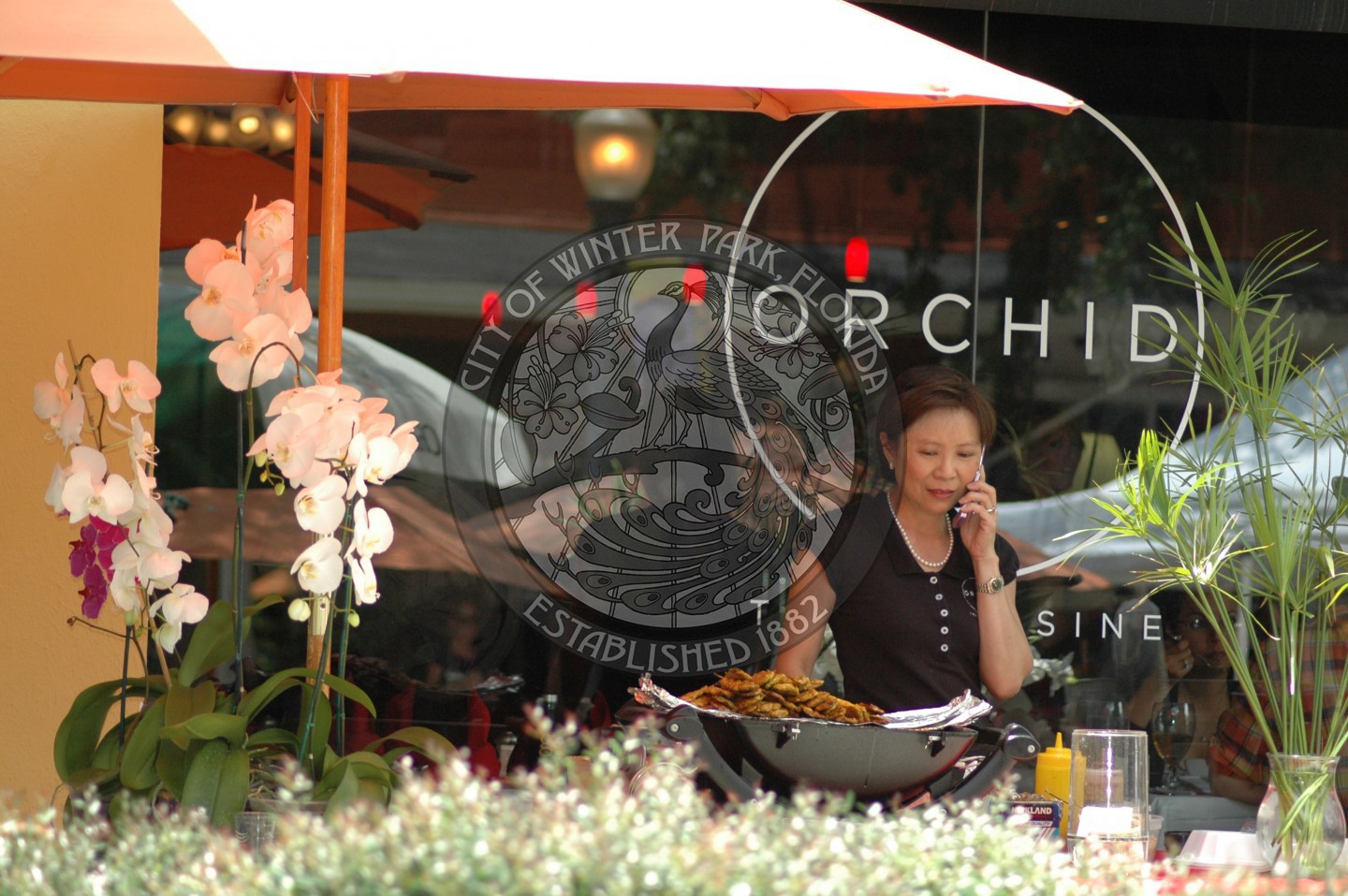 Female standing in front of Orchid Restaurant while speaking on the phone