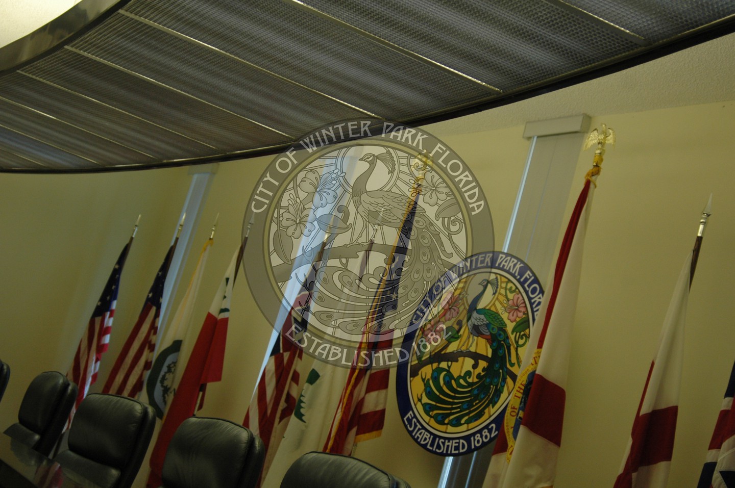 City Commission dais with the flags behind the seats
