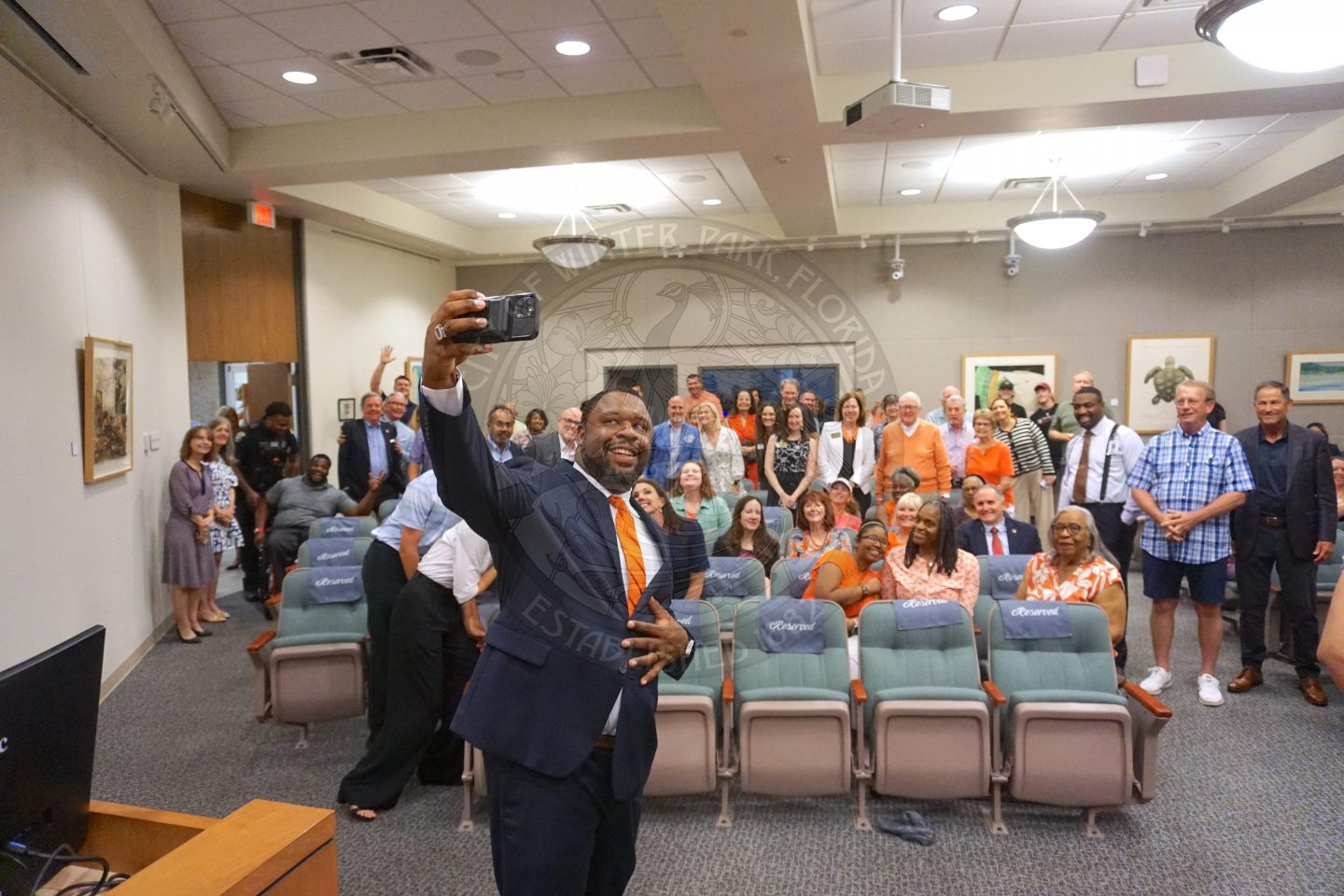 Commissioner Russell holding his phone taking a selfie with all of his supporters who came to watch him get signed into office.