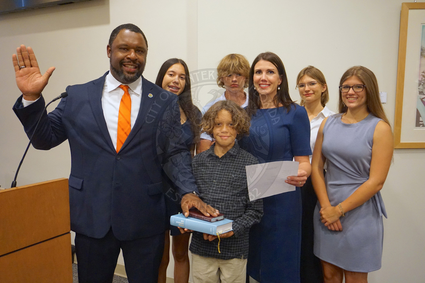Official picture of Commissioner Russell holding his right hand up and his left hand on the bible with his wife and kids.
