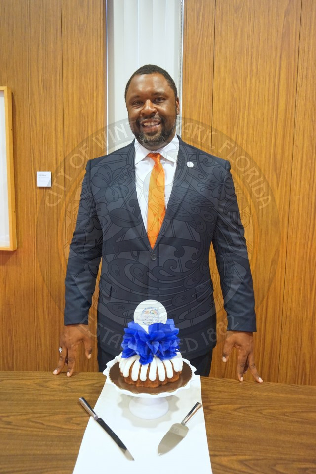 Commissioner Russell standing behind his bundt cake smiling.