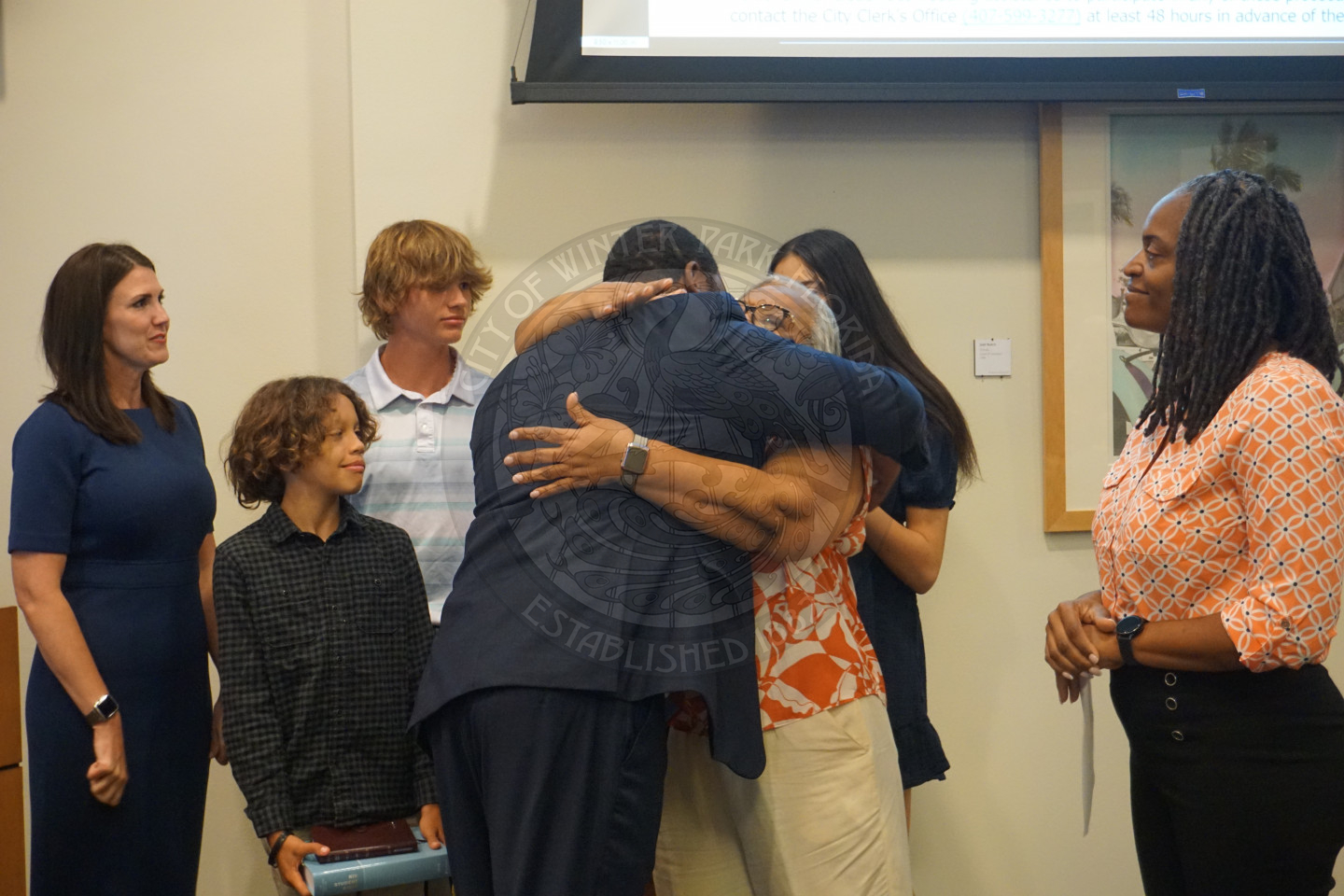 Commissioner Russell hugging his mother who was just signed into office. Behind his mother are his wife and kids.