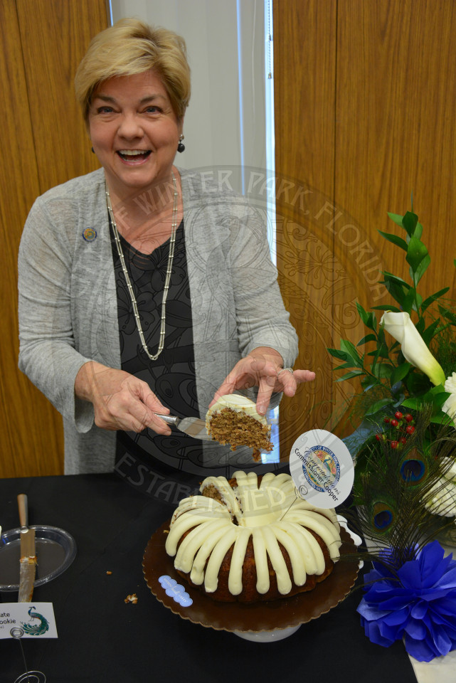 Commissioner Carolyn Cooper cuts the first slice of cake and holds it up ready to server.