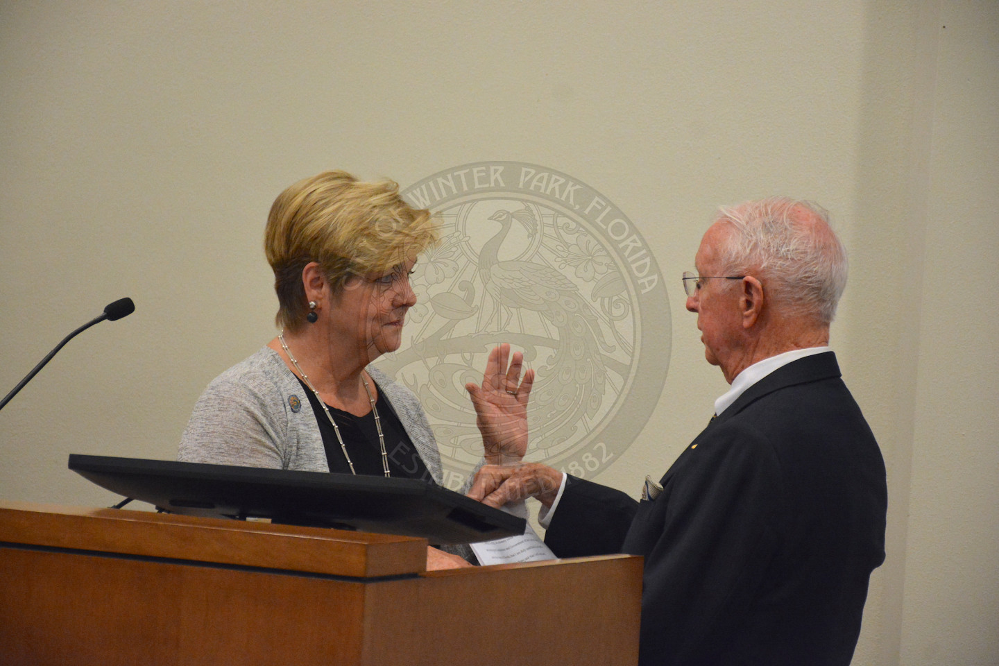 Commissioner Cooper stands at podium as she recites her Oath of Office given by gentleman in a suit and tie.
