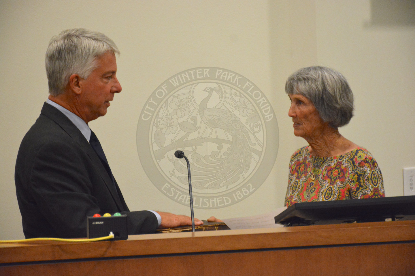 Commissioner Todd Weaver stands at podium as he recites his Oath of Office. given by a female in a floral blouse.