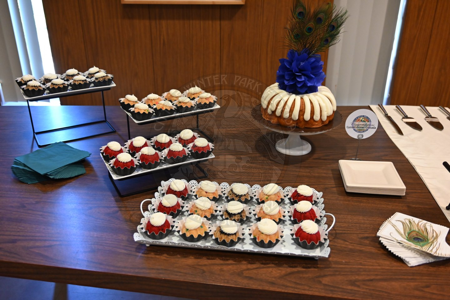 cupcakes on a platter with napkins and plates around it.