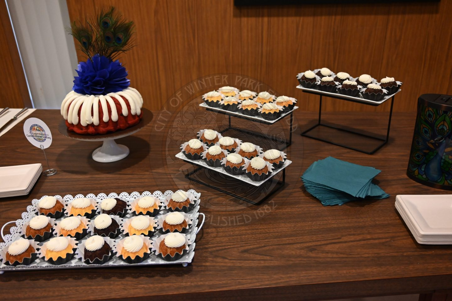 cupcakes on a platter with napkins and plates around it.