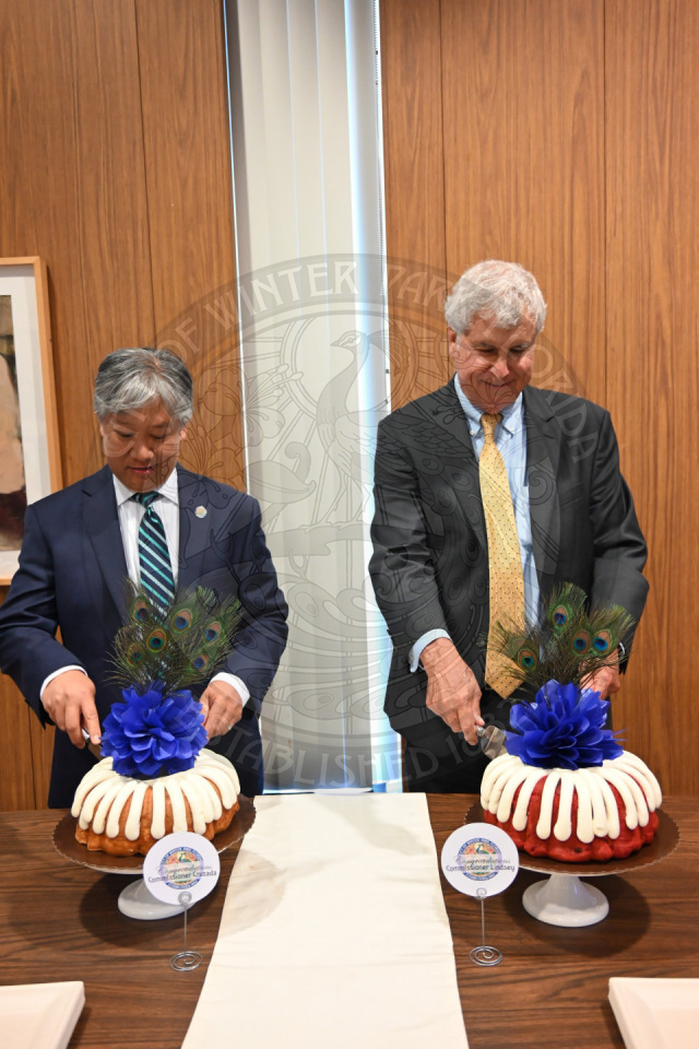 two men standing behind their personalized cakes while cutting into it.