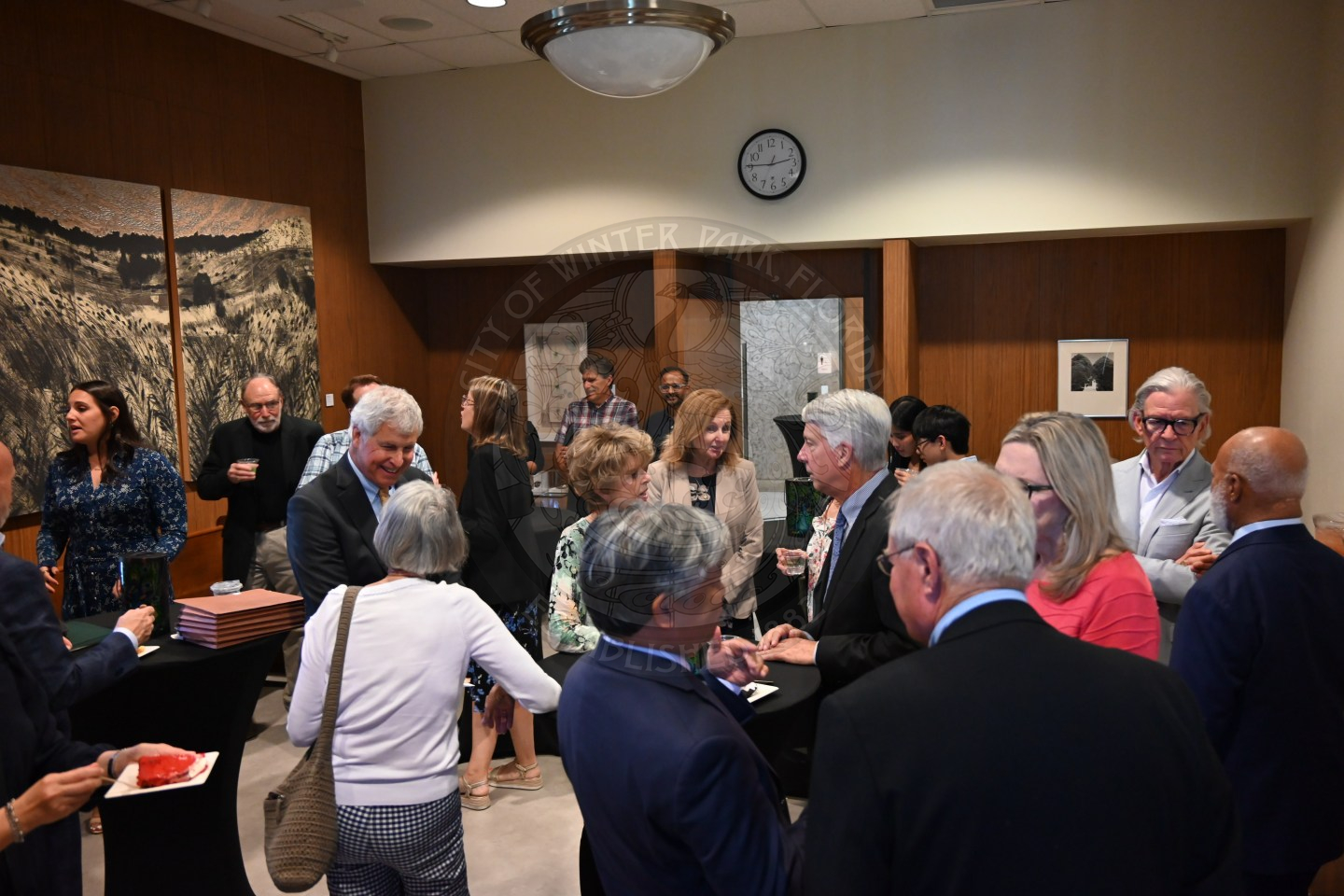 a bunch of people gathered in a room mingling.