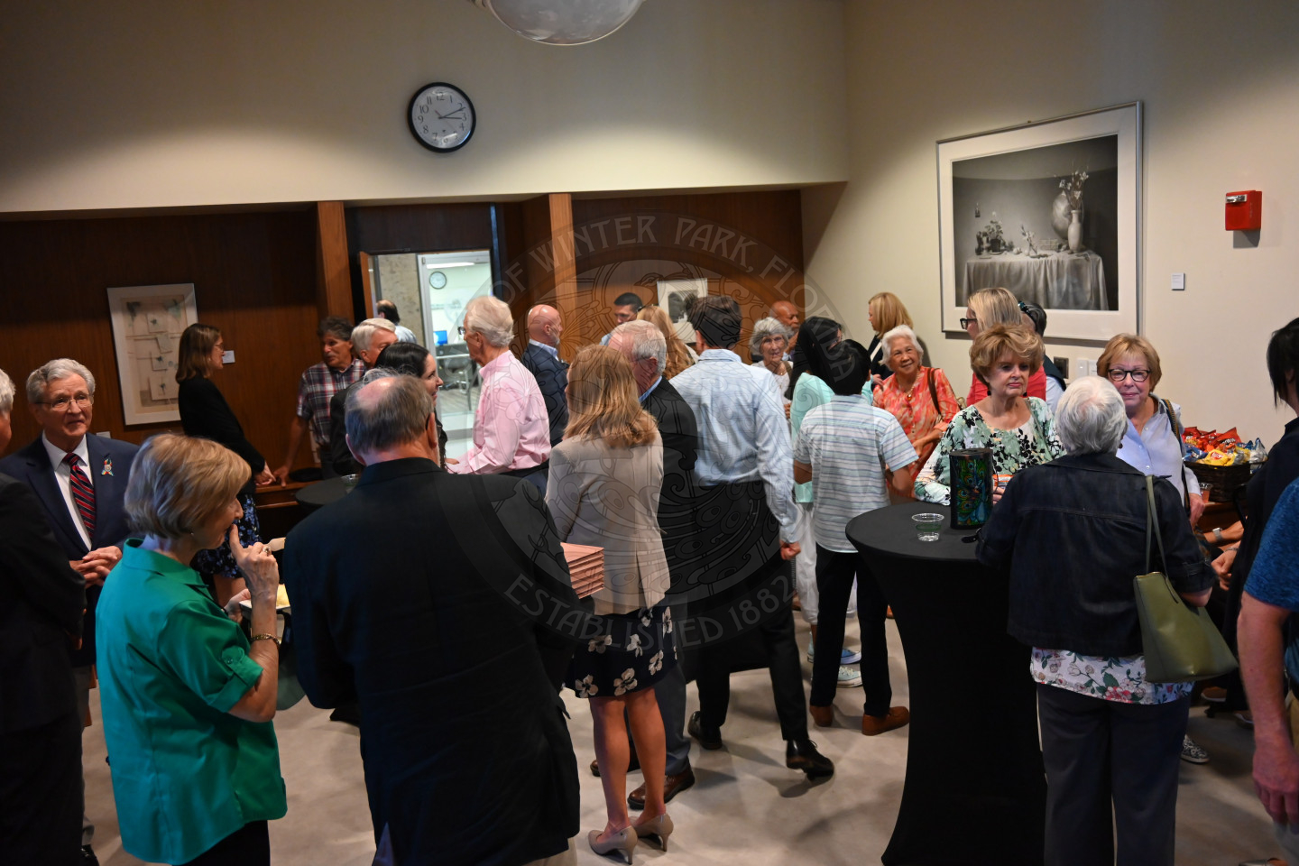 a bunch of people gathered in a room mingling.
