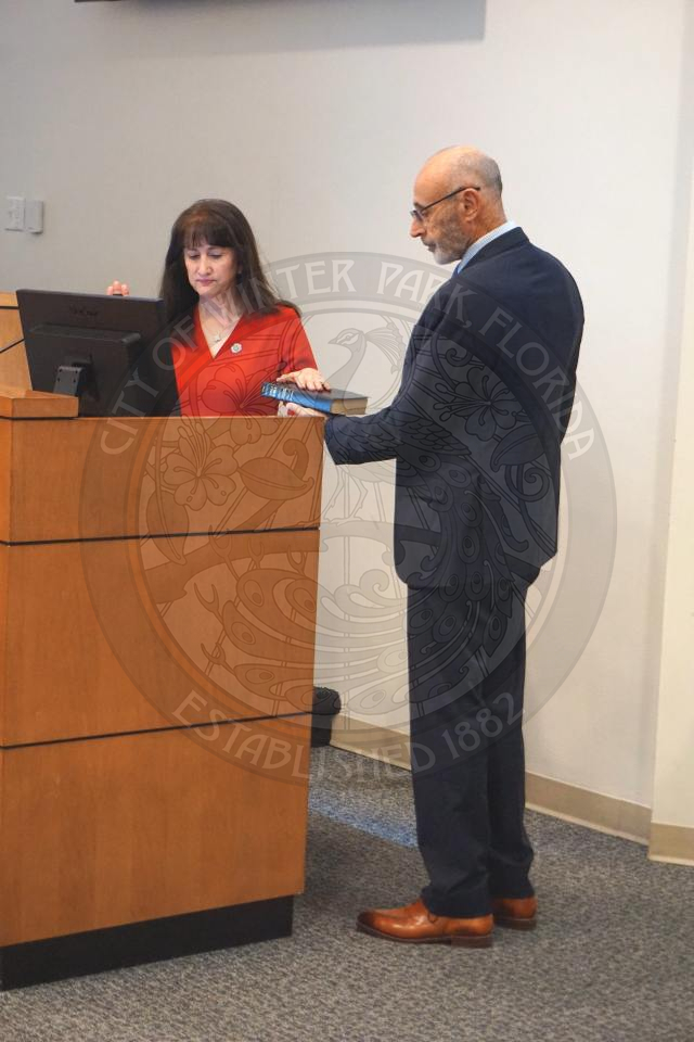 Commissioner Sheila DeCiccio holding her left hand a bible that her husband is holding and holding her right hand up while she is swearing-in to office