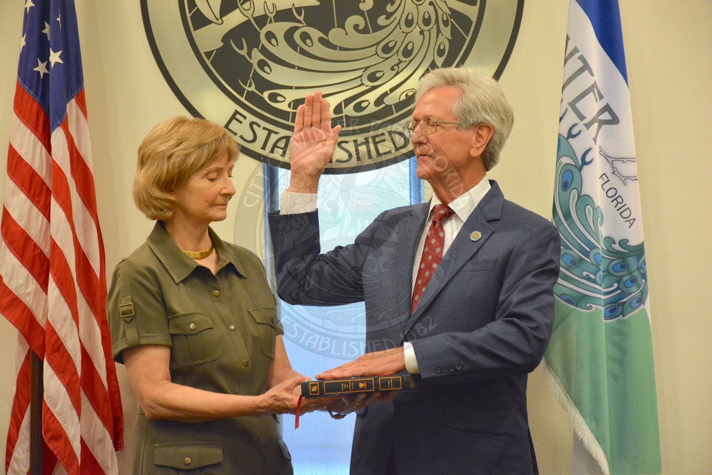 Commissioner Sullivan raising his right hand with his left hand placed on a bible his wife is holding during his official swearing in ceremony