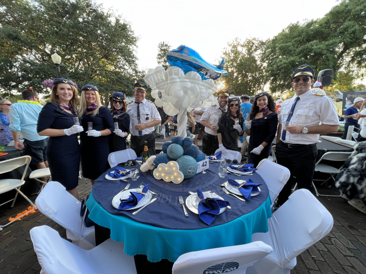 A table decorated as Pan Am Airways. The group is standing behind the table dressed in flight attendant wear.