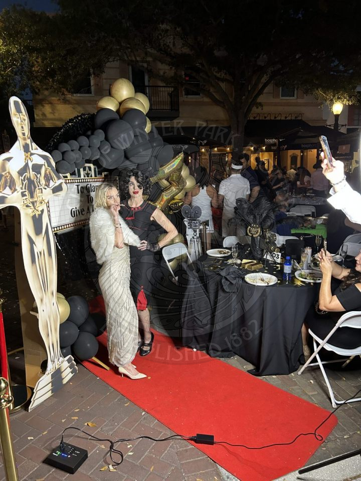 Hollywood glam table. There is a red cacrpet with 2 women who are posing for the camera.