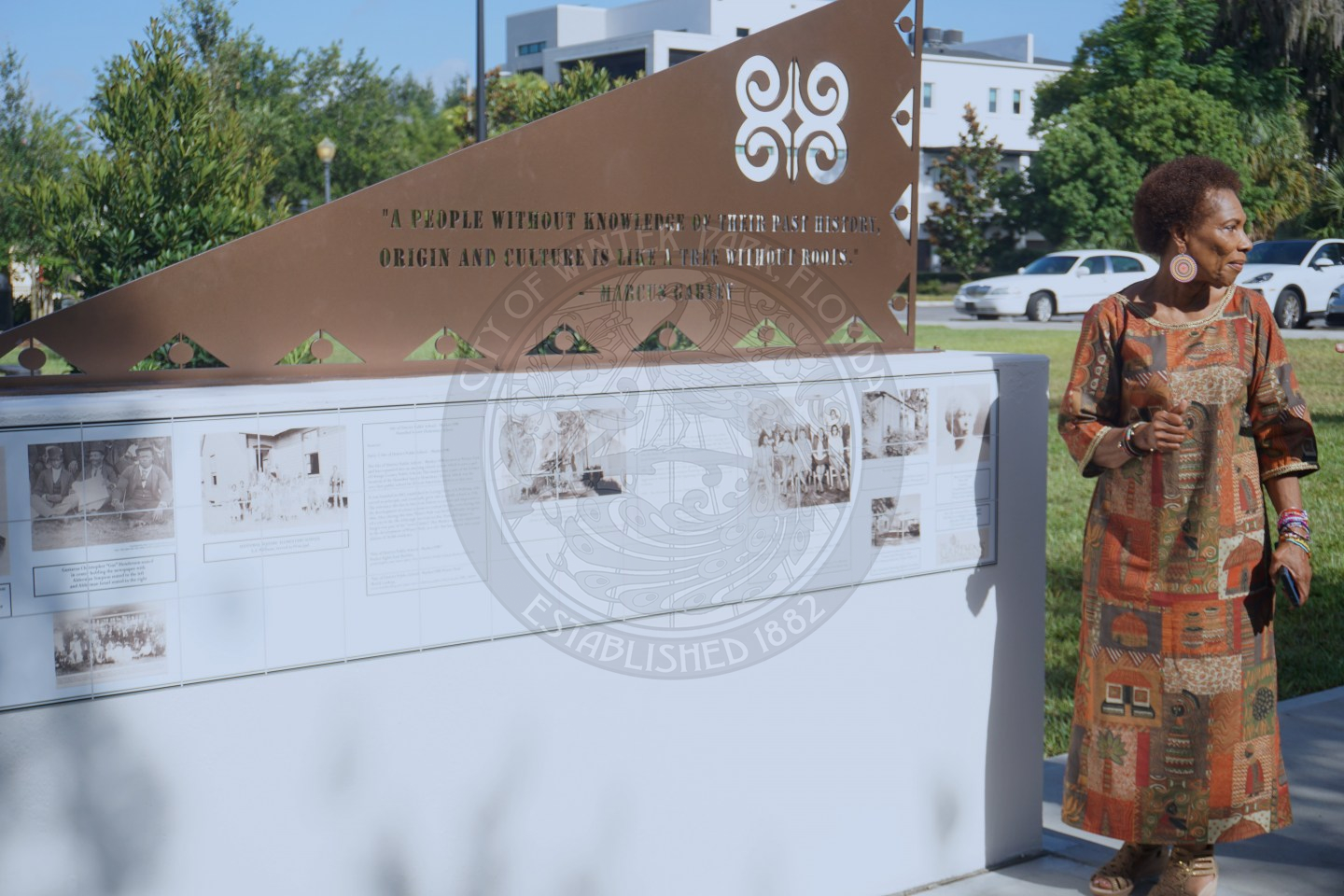 a woman standing next to a peice of art.