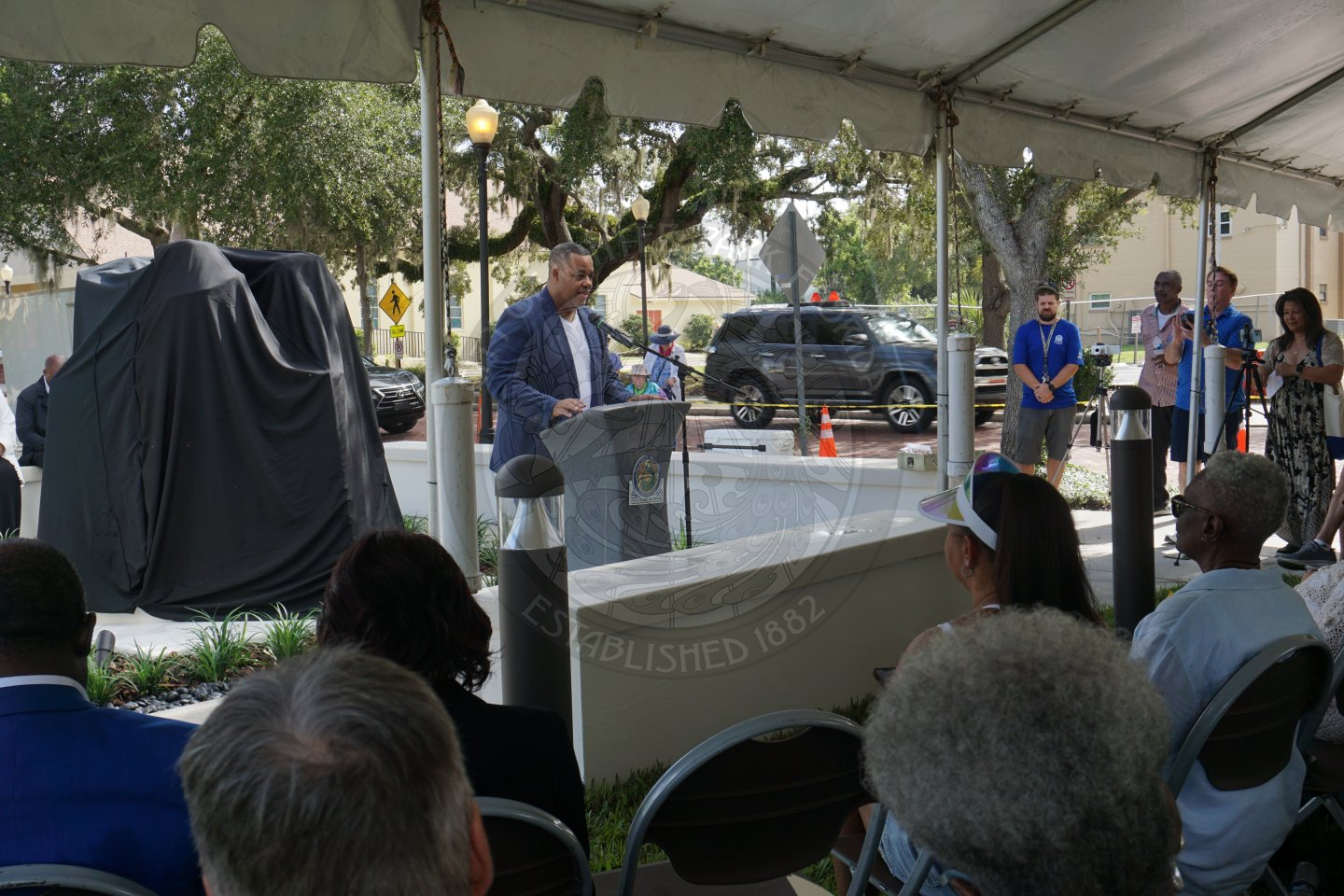 a man standing behind podium speaking into a microphone.