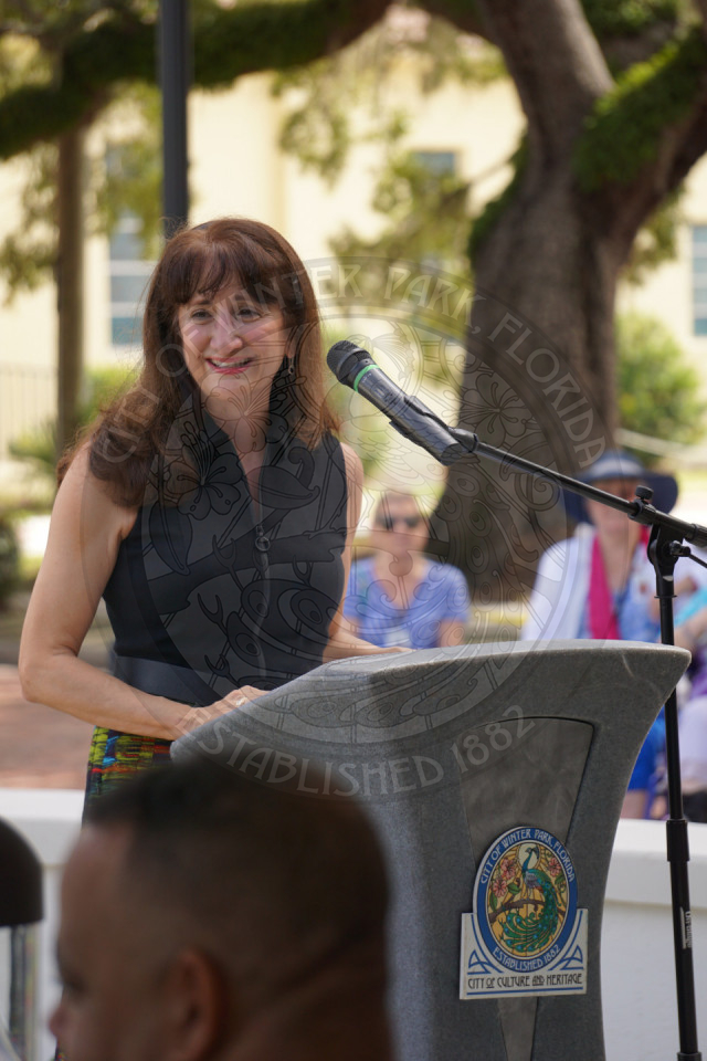 A woman standing behind a podium smiling while looking off to the side.