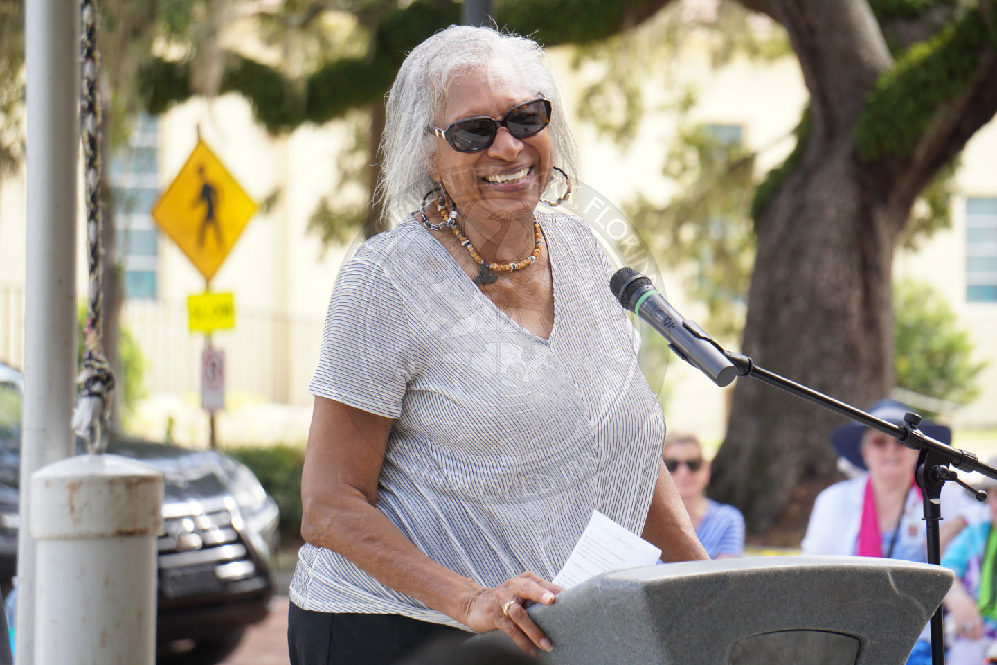 A woman standing behind a podium smiling into the audience.