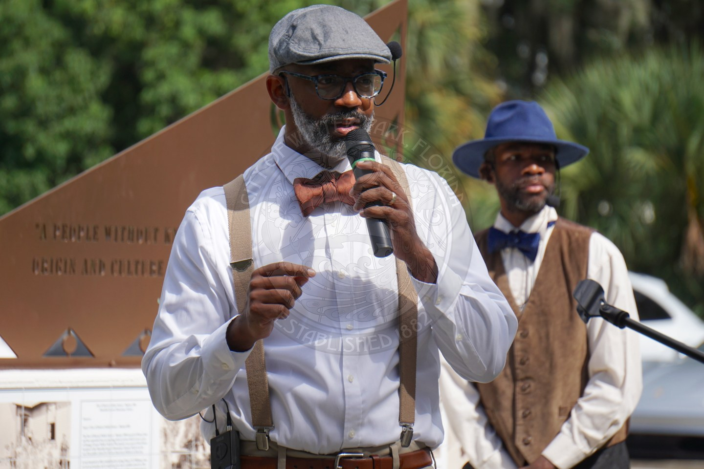 a man speaking into a mircophone talking to a crowd.