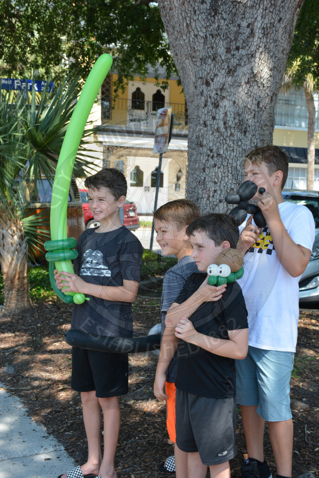 Four young boys with holding up balloon animals while smiling