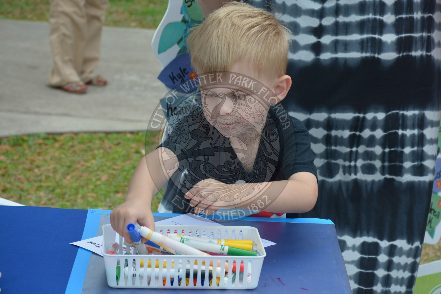 Young boy reching for coloring markers at arts &amp; crafts table