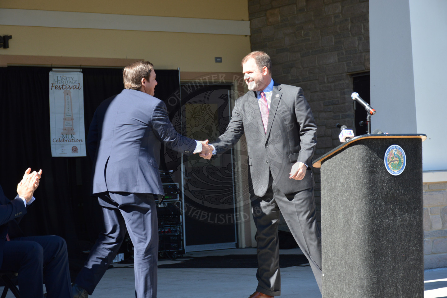 Mayor Steve Leary shaking hands with Governor Ron DeSantis at the podium