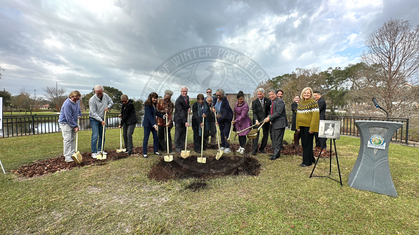 Group of people holding gold shovels to dig into the ground for a groundbreaking ceremony