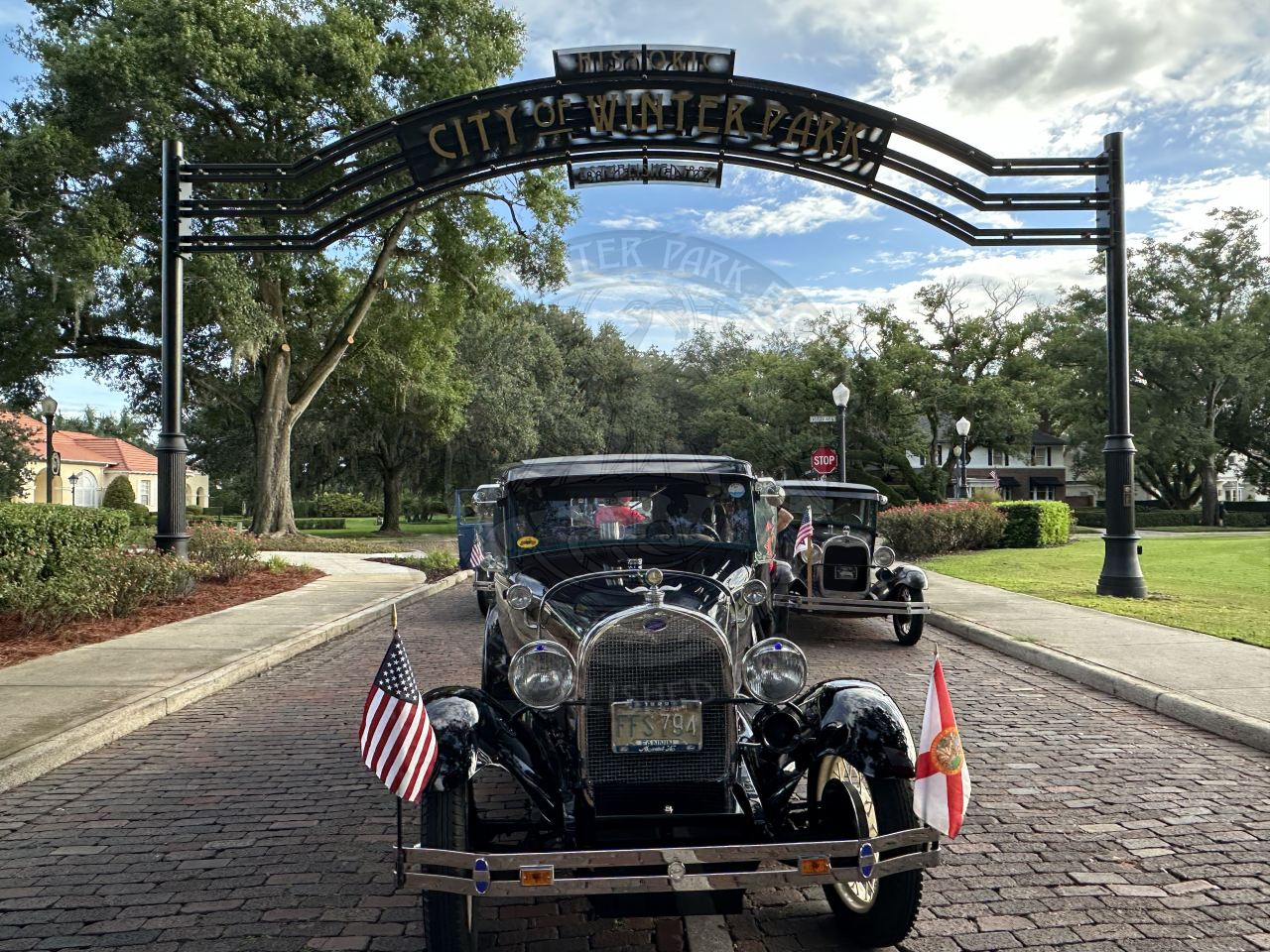 old cars parked underneath the City of Winter Park gateway sign