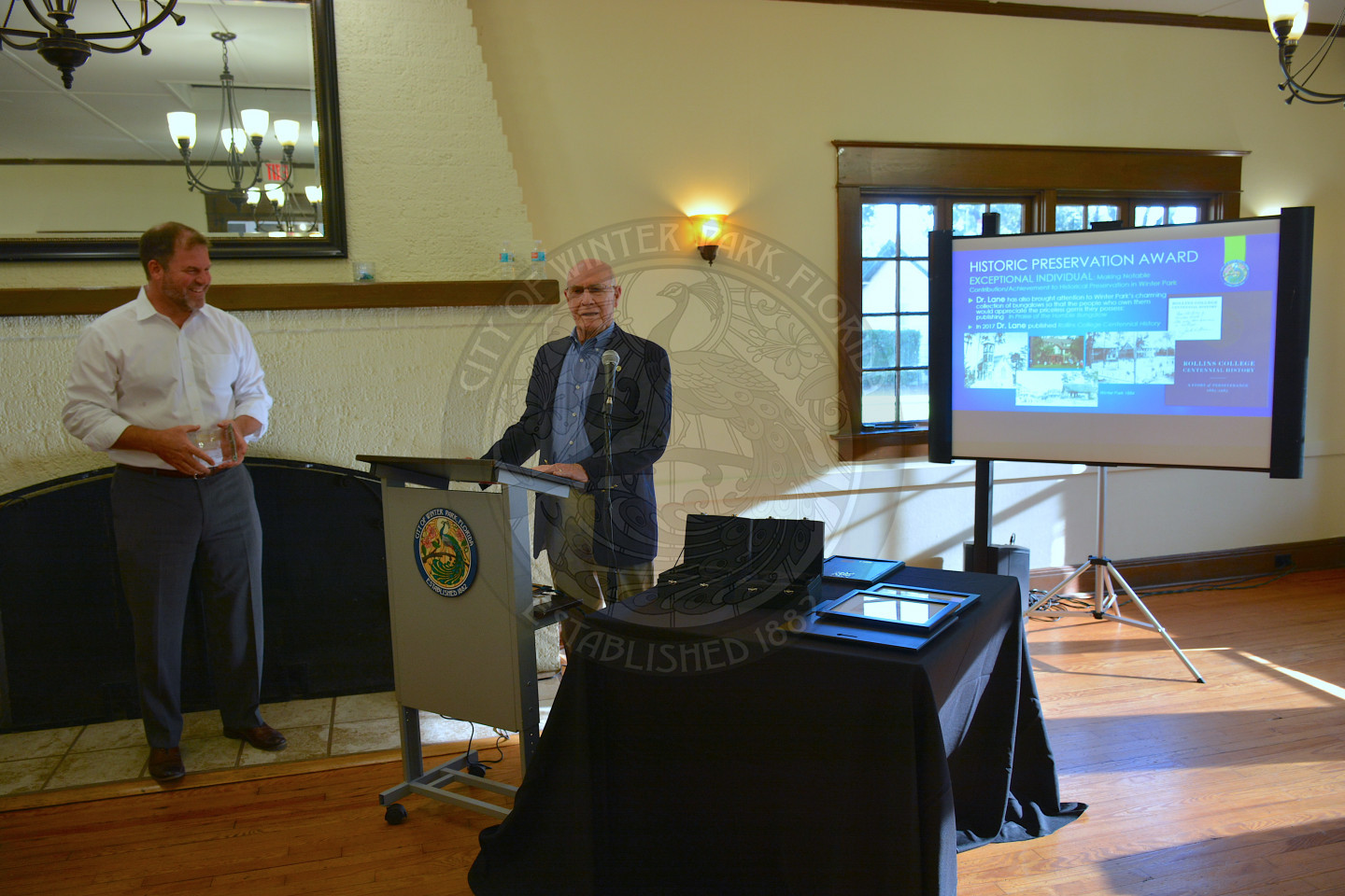 Male speaker at the podium sharing remarks, Mayor Steve Leary standing next to him.