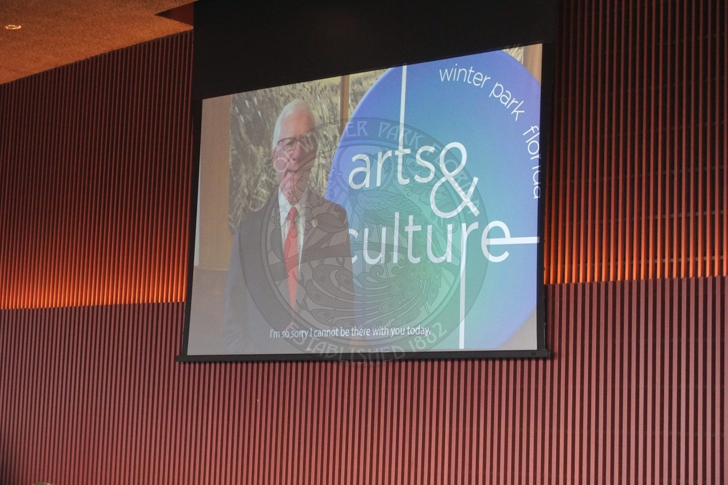 A pull down screen with a video playing and the Mayor talking about missing the event.