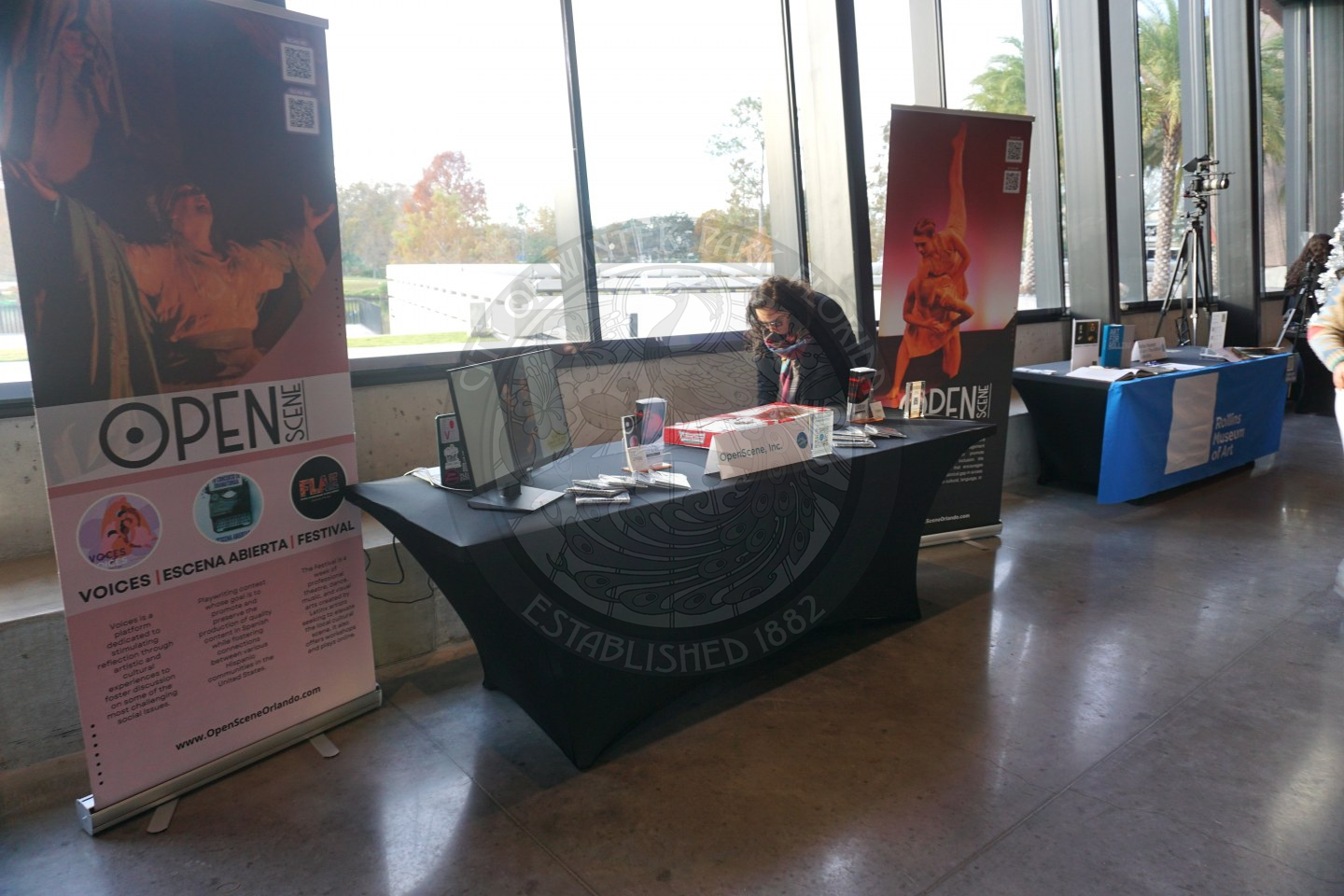 A table with a black linen that has pamplets and information about the company. Next to the table is 2 banners on each side that have information about Open Scene. 