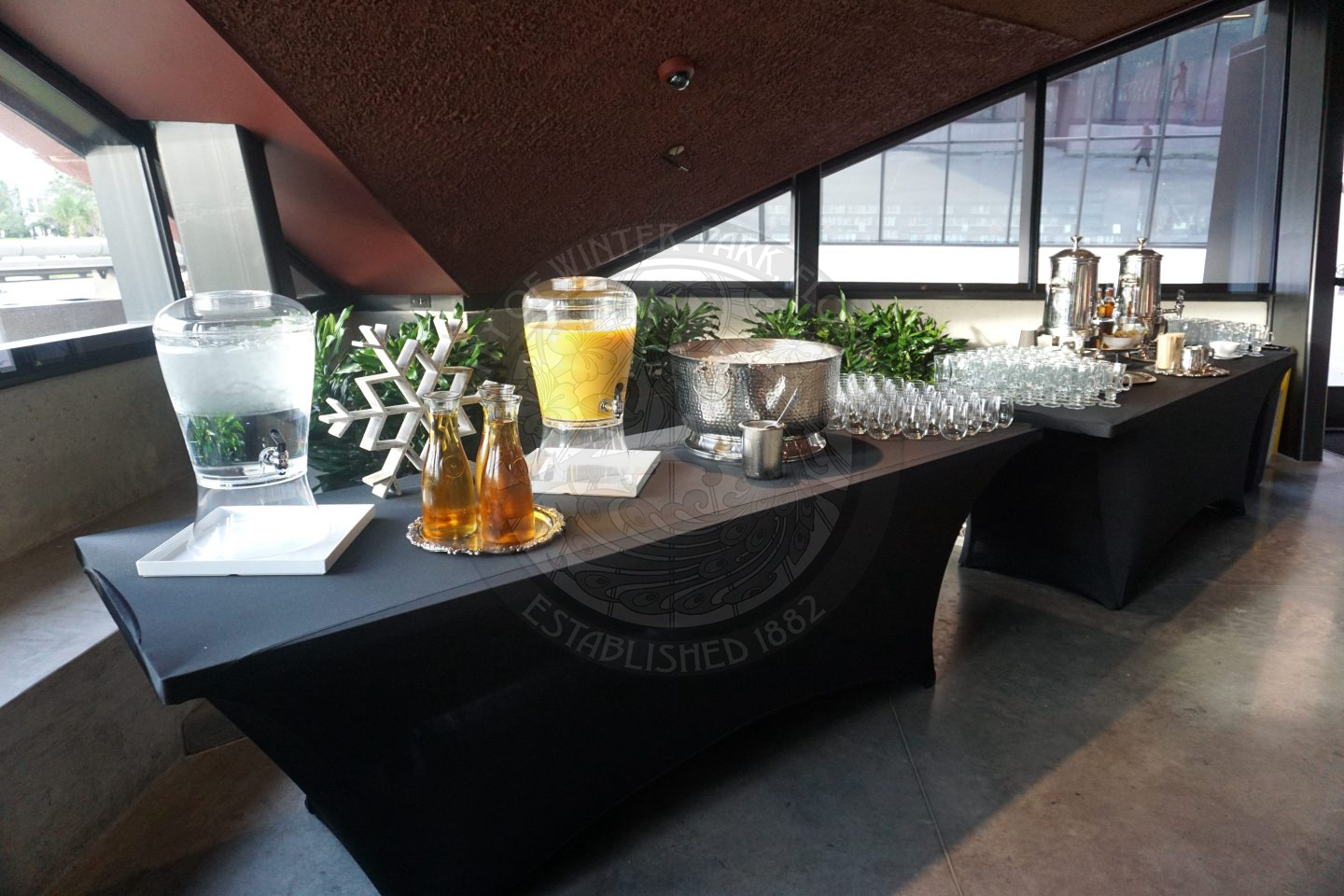 Two tables with drinks on it and glasses.