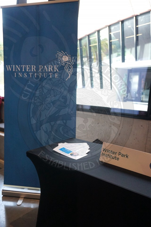 a banner that says Winter Park Institue next to a table with paper information.