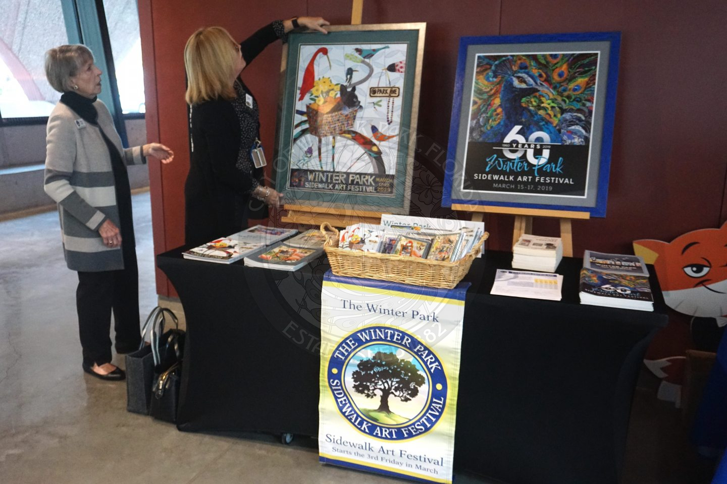 Winter Park Sidwalk Art Festival information at a table with postcoards and photos.