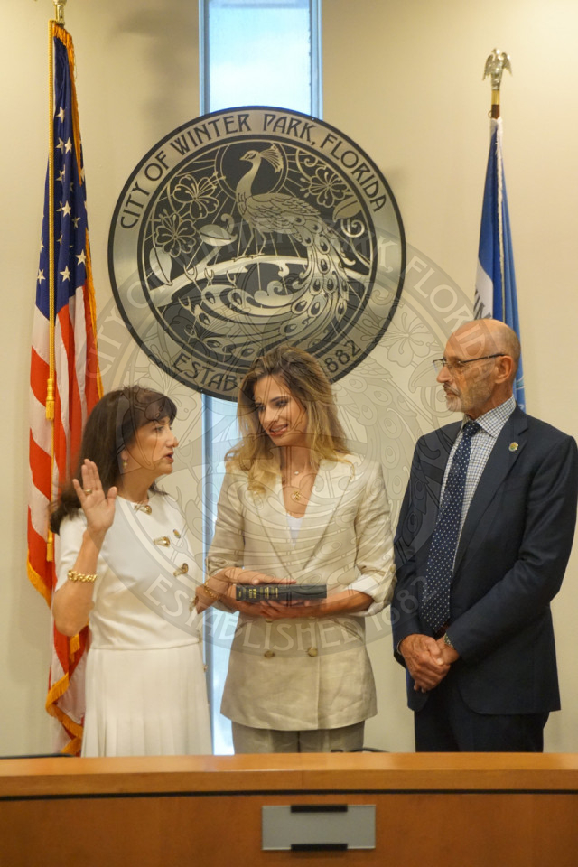 Mayor DeCiccio holding her right hand up and her left hand on a bible that her daughter is holding. Mayor's husband is standing right next to their daughter looking at the mayor take an oath.
