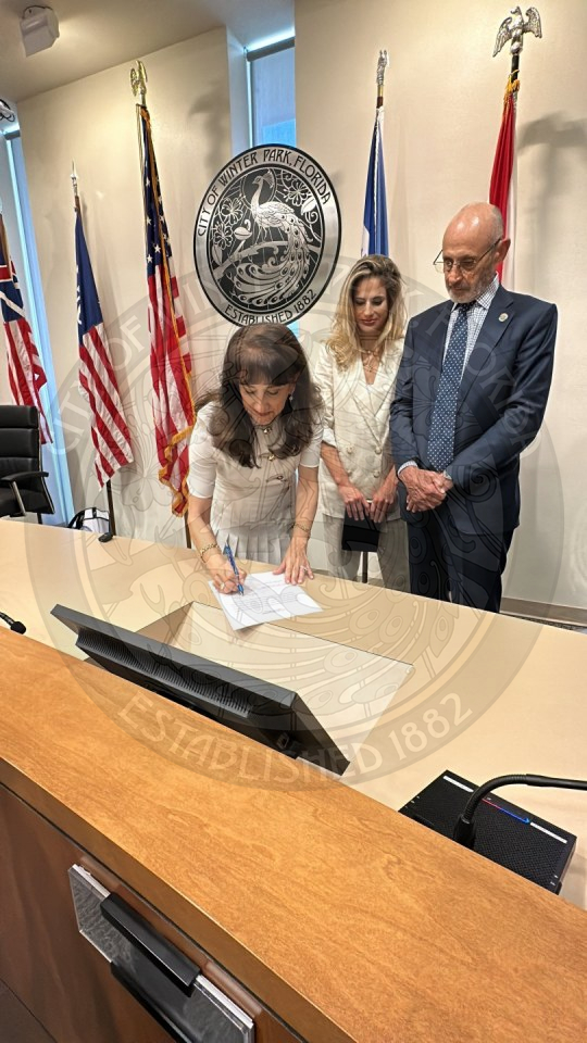 Mayor Deciccio signing her oath of office with her daughter and husband standing behind her.