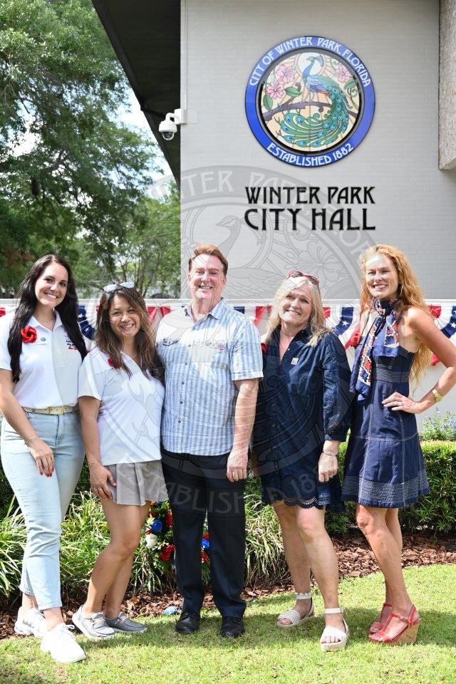 Five people smile and pose together outside Winter Park City Hall, with a city seal visible on the building behind them.