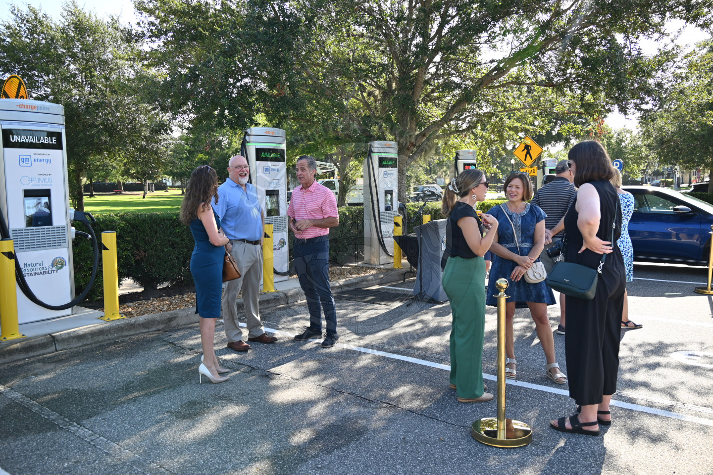 people mingling with each other standing in front of the ev chargning stations