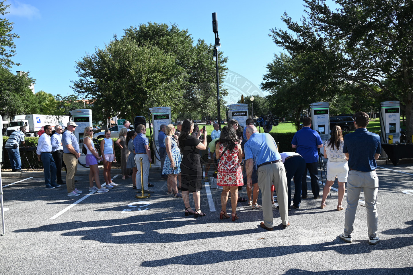 a bunch of people standing in front of ev charging stations