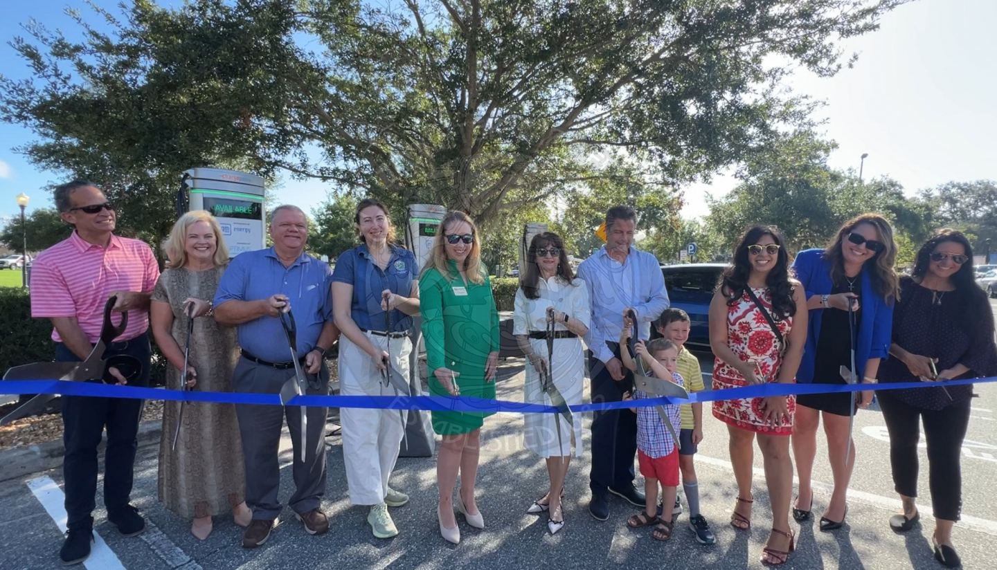 a group of people holding scissiors in their hands to cut a ribbon they are standing in front of.