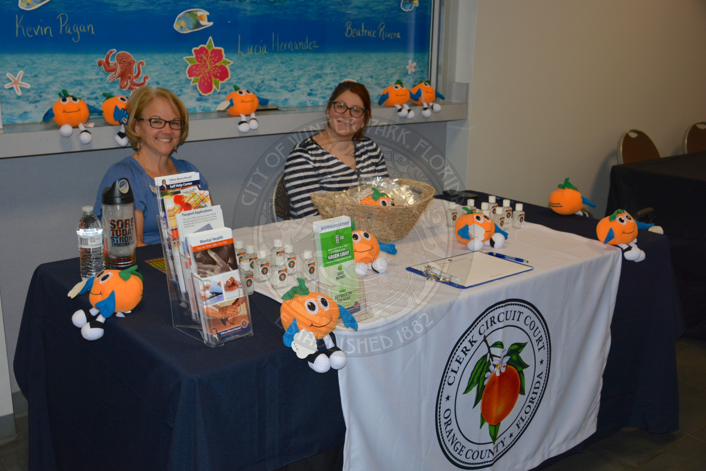 two women sitting at display table for Orange County Clerk of Courts