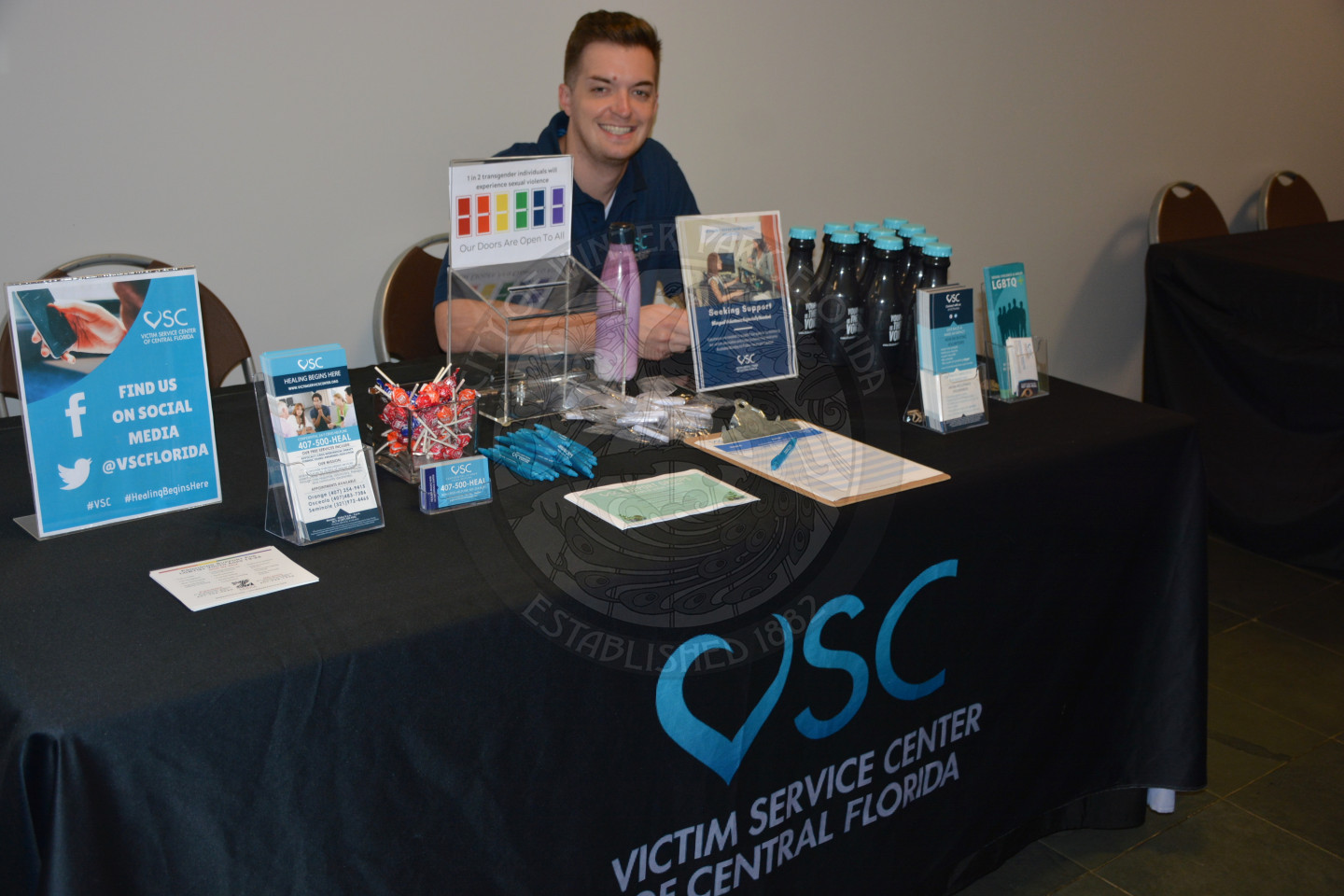 man sitting at display table for Victim Service Center of central Florida