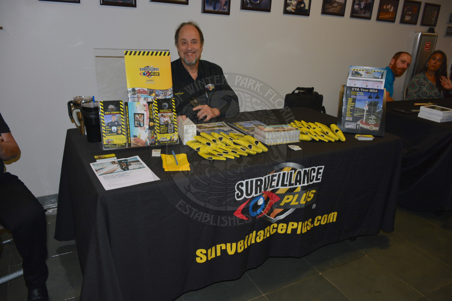 man sitting at display table for Surveilance Plus